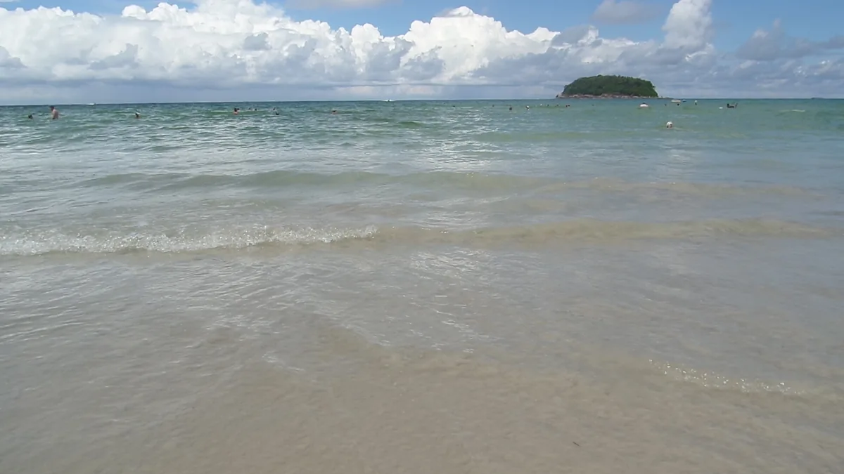 Small waves at Kata Beach with a green island offshore, Phuket